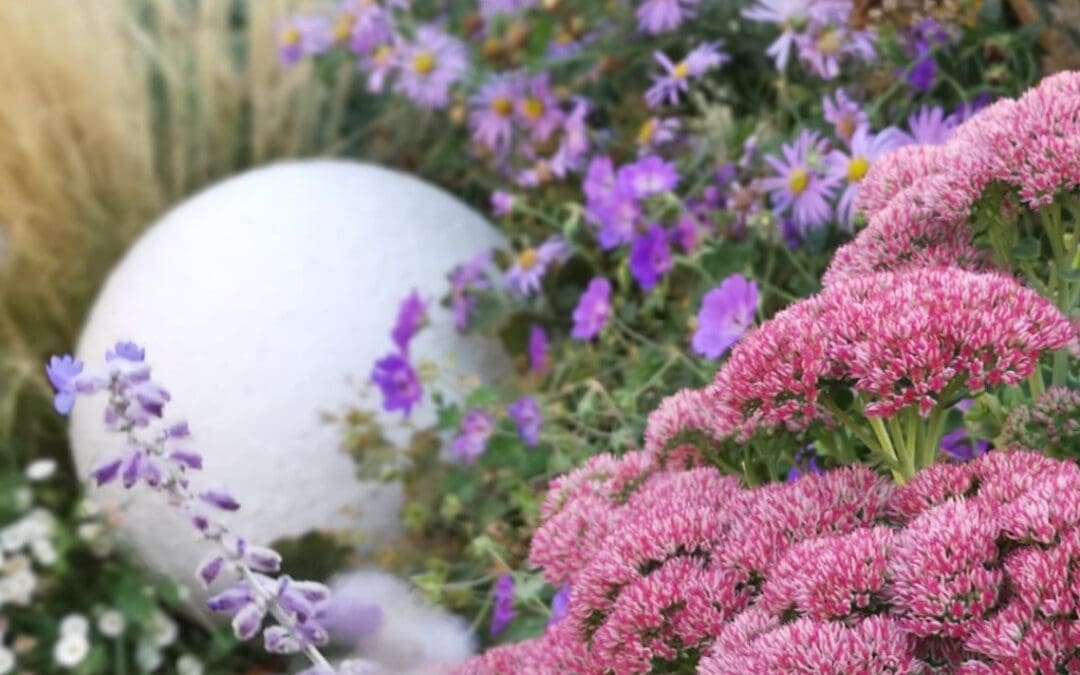 A spherical garden light with purple and pink flowers